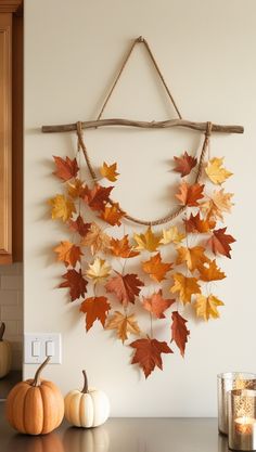 a wall hanging made out of branches with leaves and pumpkins on the counter top