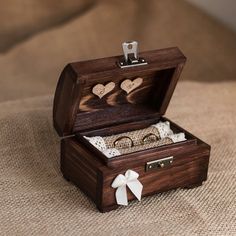 an open wooden box with two rings inside on a brown cloth covered tableclothed surface