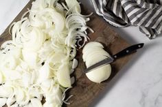 chopped onions are on a cutting board with a knife next to it and a striped dish towel