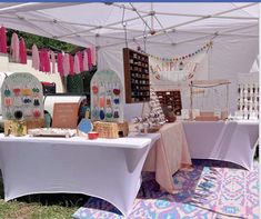 an outdoor market with tables covered in white tents and colorful rugs on the ground