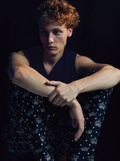 a young man sitting on the ground with his arms crossed