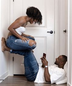 a woman sitting on top of a man's lap looking at his cell phone