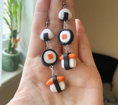 a person is holding up some cute little sushi charms in their hand and they are wearing black, white, and orange