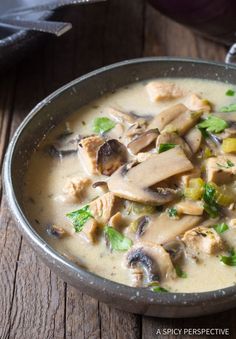 a metal bowl filled with soup on top of a wooden table