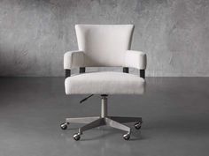 a white office chair with wheels in front of a gray wall and concrete flooring