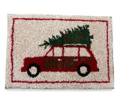 a red car with a christmas tree on top is hooked up to a door mat