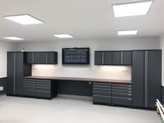 an empty garage with lots of cabinets and lights on the ceiling is pictured in this image