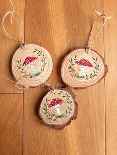 two wooden slices with mushrooms on them are hanging from twine strings in the middle of a wood floor