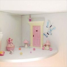 there is a doll house with pink doors and decorations on the shelf in front of it