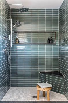 a tiled shower with a bench in the corner next to it and shelves on the wall