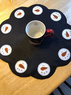 a coffee cup sitting on top of a black mat with white and brown circles around it