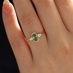 a woman's hand with a ring on it and a green stone in the middle