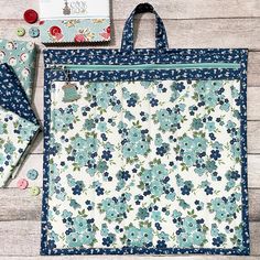 a blue and white flowered tote bag next to two matching fabric pieces with buttons on them