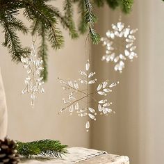 a snowflake ornament hanging from a christmas tree with pine cones on it