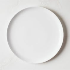 an empty white plate sitting on top of a table