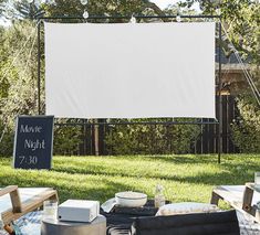 an outdoor movie is set up in the backyard with chairs, tables and a projection screen