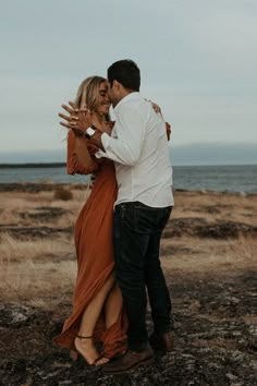 a man and woman embracing each other in front of the ocean