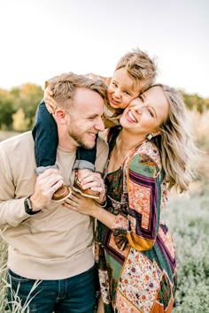 a man, woman and child are smiling while holding each other in an open field