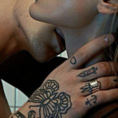 a man and woman kissing each other with tattoos on their arms, both wearing rings