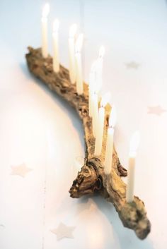 a group of lit candles sitting on top of a piece of driftwood with stars around it