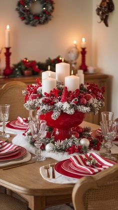 a dining room table decorated for christmas with red and white plates, silverware and candles