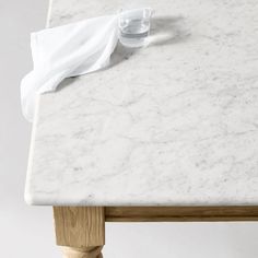 a white marble table with wooden legs and a napkin on the top that is rolled up