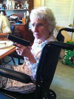 an older woman sitting in a chair holding a remote control