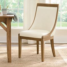 a wooden table with a white chair next to it and a window in the background