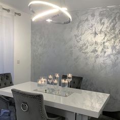 a dining room table and chairs with candles on the table in front of wallpaper