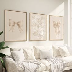 three framed pictures hang on the wall above a white couch with pillows and throw blankets