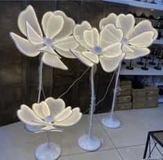 three metal sculptures with flowers on them in a store display area, one is lit up and the other is made out of wire