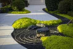 a garden with rocks and green plants in the center, surrounded by white walkways