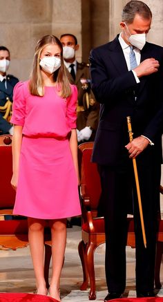 a man in a suit and tie standing next to a woman wearing a face mask