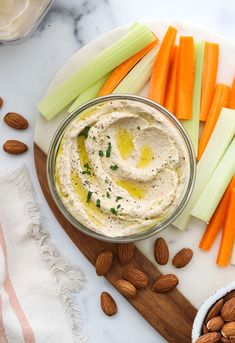 carrots, celery, and almonds on a cutting board with dip