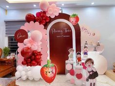 there are many balloons and decorations on display in this room, including an arch with strawberrys