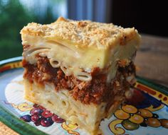 a piece of lasagna sitting on top of a blue and yellow plate with flowers