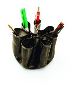 a black cup filled with pens and pencils on top of a white table next to another cup