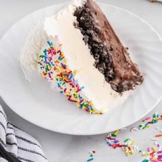 a slice of cake with white frosting and sprinkles on a plate