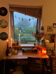 a desk with candles and pictures on the wall next to it, in front of a window