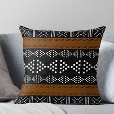 a black and brown throw pillow sitting on top of a couch next to a white pillow