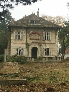 an old abandoned house sitting in the middle of a field with lots of leaves on the ground