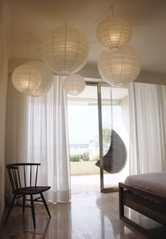 three lamps hanging from the ceiling above a bed in a room with white drapes