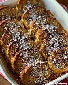 french toast with powdered sugar on top in a white casserole dish, ready to be eaten