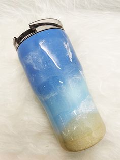 a blue and yellow drink bottle sitting on top of a white fur covered floor next to a cup