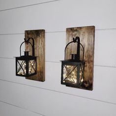 two lanterns are hanging on the wall next to each other, one has a lantern in it