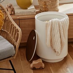 a white bucket sitting on top of a wooden floor next to a chair and table