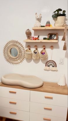 a white dresser topped with lots of drawers and shelves next to a wall mounted mirror