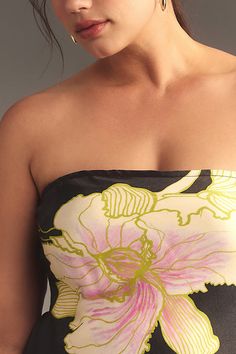 a woman in a strapless dress with a flower on it's chest and large earrings