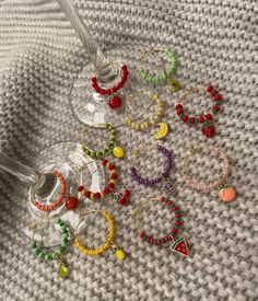 wine glass filled with lots of different colored beaded bracelets and earrings on top of a white blanket