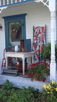 a porch with potted plants and an old table on the front step next to it